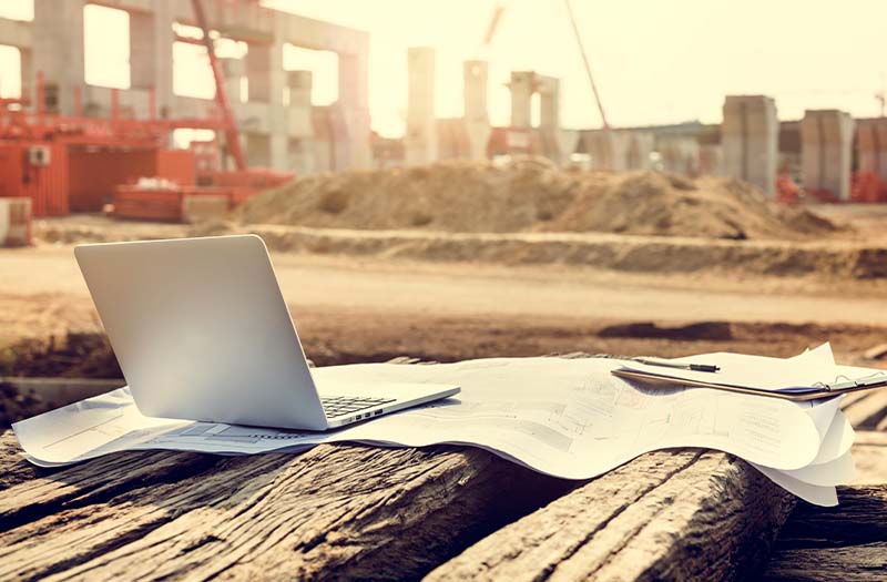 Cantiere con progetti e laptop al tramonto