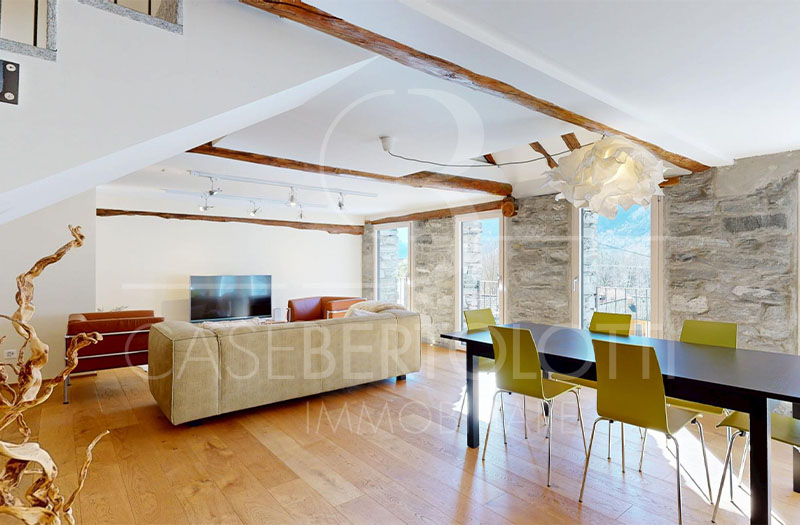 Heller Wohn- und Essbereich mit Natursteinwand und Holzbalken