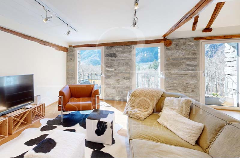 Helles Wohnzimmer mit Natursteinwand und Bergblick